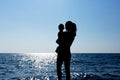 A young girl holds a child in her arms against the sun. Silhouette photography