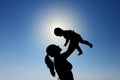 A young girl holds a child in her arms against the sun. Silhouette photography