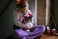 Cute girl holds dog in Santa red hat and looks out the window waiting for holiday, Christmas miracle Royalty Free Stock Photo