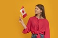 Young girl holds the flag of Canada in bright orange background. Study in Canada. Student exchange program