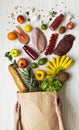 Young girl holds full paper bag of groceries on white wooden table, overhead view. From above. Top view. Flat lay Royalty Free Stock Photo