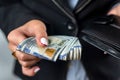 young girl holds a large sum of dollars in her hands and counts money in a black purse. Royalty Free Stock Photo