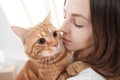 A young girl holds a sneaky red cat in her arms.