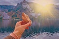 Young girl hollding faded pale leaf in her hand in the bright light of beautiful scenic sunset sun over Austrian alps lake.