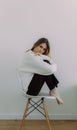 A young girl immersed in her thoughts sits on a chair on a white background, space for text. The concept of self-knowledge. Visual