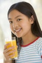 Young girl indoors drinking orange juice smiling Royalty Free Stock Photo