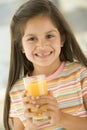 Young girl indoors drinking orange juice smiling Royalty Free Stock Photo