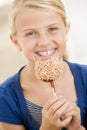 Young girl indoors eating candy apple