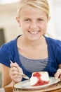 Young girl indoors eating cheesecake