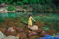 Young girl isolated standing in pristine clear waterfall water at morning in forests
