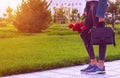 Young girl in jeans with bouquet of tulips flowers and bag walks in park