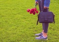 Young girl in jeans with bouquet of tulips flowers and bag walks in park