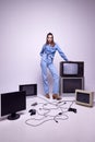 Young girl in jeans clothes posing around many retro TV sets and console. Game popularity, leisure activity