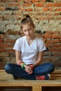 Young girl in jeans and white T-shirt is sitting on the floor and sad. Concept of a non happy teenager Royalty Free Stock Photo