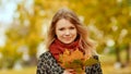 A young girl joyfully posing on the camera with a bouquet of colorful leaves. Walk in the city park in the autumn.