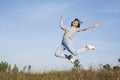 Young girl jumping at field grass with blue sky Royalty Free Stock Photo