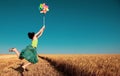 Girl jumping with pinwheel over wheat field Royalty Free Stock Photo