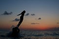 Young girl jumping in the sea beach against sunset sky with sun and clouds. Happy family having fun on sea beach Royalty Free Stock Photo