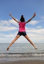 Young girl jumping very high with open arms and legs by the sea Royalty Free Stock Photo