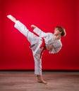 Young girl karateka in a white kimono and a red belt trains and performs a set of exercises on a bright red background Royalty Free Stock Photo