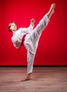 Young girl karateka in a white kimono and a red belt trains and performs a set of exercises on a bright red background Royalty Free Stock Photo