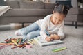 Young girl, kid and pencils on floor with coloring book in living room for education, learning or creative development Royalty Free Stock Photo