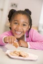 Young girl in kitchen eating cookies smiling