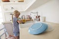 Young girl kneeling on a chair washing up at kitchen sink Royalty Free Stock Photo