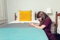 A young girl kneeling and praying to God at the side of a bed in her bedroom Royalty Free Stock Photo