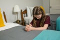 A young girl kneeling and praying to God at the side of a bed in her bedroom Royalty Free Stock Photo