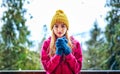 Young girl in a knitted cap and mittens standing under snowing Royalty Free Stock Photo