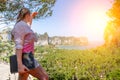 A young girl with laptop in a white shirt and pink t-shirt stands on top of a mountain overlooking a tropical beach and jungle. Royalty Free Stock Photo