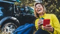 Young girl laughs showing teeth calling on mobile phone summer forest. Happy tourist with backpack calling on cellphone Royalty Free Stock Photo