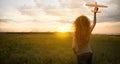 A young girl launches an airplane into the sky while walking in the summer at sunset. Curly woman with a toy in her Royalty Free Stock Photo