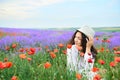 Young girl is in the lavender field with red poppy flowers, beautiful summer landscape Royalty Free Stock Photo