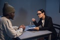 A young girl lawyer consults her client at the police station, a black guy in a cap and handcuffs.