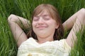 Young girl laying back in the grass arms behind her head , smiling and dreaming Royalty Free Stock Photo