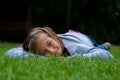 Young girl lays on stomach in grass smiling