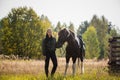 A young girl leads her horse by the bridle along a path along the fence