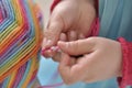 Young girl learning to crochet with multicoloured wool yarn. Homemade handiwork can be a nice and creative present