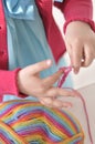 Young girl learning to crochet with multicoloured wool yarn. Homemade handiwork can be a nice and creative present