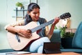 Young girl learning to play acoustic guitar at home from digital tablet through video call - concept of new normal, online or Royalty Free Stock Photo