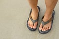 Young girl legs in flipflop sandals on sea beach