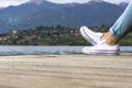 Young girl legs on a pier with blue jeans and white shoes Royalty Free Stock Photo