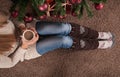 Young girl legs with warmers on floor on carpet with cup of coffee in hand and next to Christmas tree Royalty Free Stock Photo