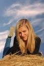 Young girl lie prone on straw bale, front view