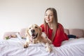 Young girl lies on a bed with golden retriever dog and smiles, a woman with a pet rest at home Royalty Free Stock Photo