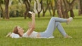 A young girl lies on her back in the green grass with a smartphone in her hands. Fun posing on camera phone. Recreation Royalty Free Stock Photo