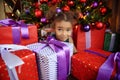Young girl lies near a Christmas tree and looking at camera