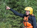 Young girl in a life jacket and helmet standing with his hand raised